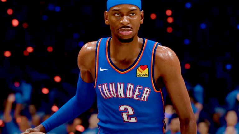 Close-up of a basketball player in an Oklahoma City Thunder uniform with number 2, wearing a blue headband and blue arm sleeve, on a court with blurred crowd in the background.